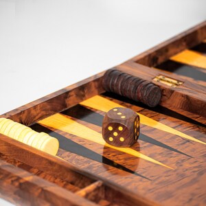 Pu&ograve; includere: Un tabellone da gioco di backgammon in legno con una superficie di gioco nera e gialla. Un solo dado con punti gialli &egrave; sul tabellone. Ci sono anche pile di pedine nei scomparti laterali.