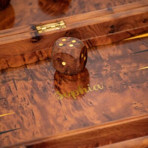 Pu&ograve; includere: Un tabellone da backgammon in legno con intarsi dorati e il nome "Sophia" inciso sulla superficie. Un dado di legno con quattro punti &egrave; sul tabellone.