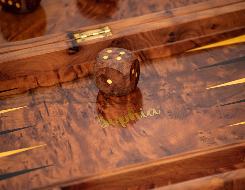 Pu&ograve; includere: Un tabellone da backgammon in legno con intarsi dorati e il nome "Sophia" inciso sulla superficie. Un dado di legno con quattro punti &egrave; sul tabellone.