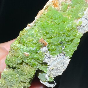 May include: A close-up of a green mineral specimen with a rough, textured surface. The mineral is clustered together in a dense formation, creating a visually interesting and unique piece.