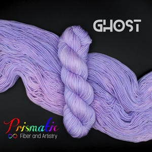 May include: A skein of Ghost-coloured yarn, a light lavender hue, is displayed against a black background. The yarn is from Prismatic Fiber and Artistry. The word "GHOST" is written in white, and the yarn is a soft, delicate fibre.