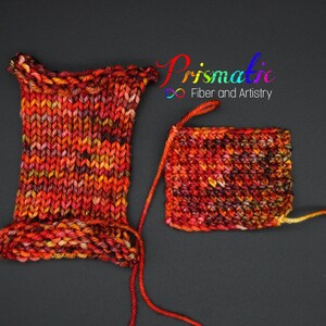 May include: Two swatches of yarn in a multi-colored blend of red, orange, yellow, and black. The yarn is knit into a square and a rectangle. The text "Prismatic Fiber and Artistry" is visible in the top right corner of the image.