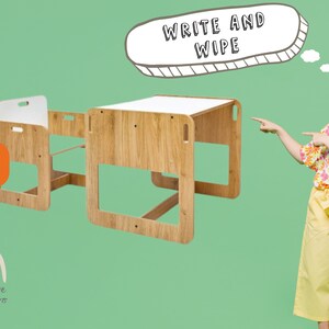 May include: A wooden children's table and chair set with a white top. The table has a "Write and Wipe" sign above it. The set is on a green background.