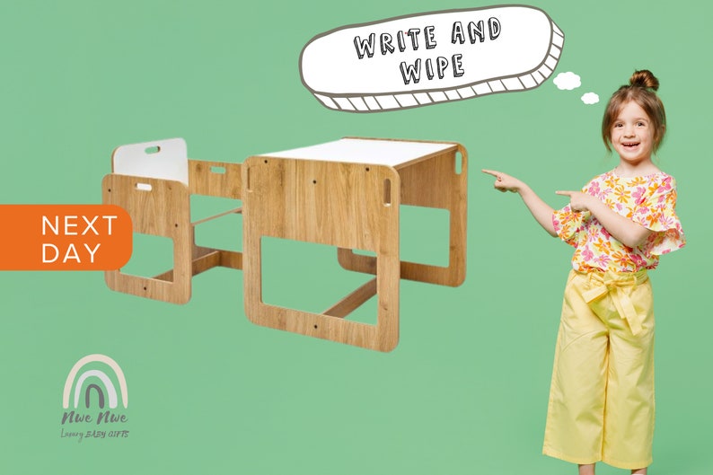 May include: A wooden children's table and chair set with a white top. The table has a "Write and Wipe" sign above it. The set is on a green background.