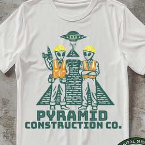 May include: White t-shirt featuring a green graphic of two alien construction workers in orange vests and yellow hard hats, standing in front of a pyramid and a UFO. The text "PYRAMID CONSTRUCTION CO." is below the graphic.
