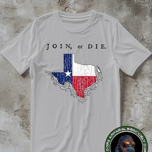 Puede incluir: Una camiseta gris con un diseño de bandera de Texas desgastado y el texto "JOIN, or DIE." La bandera tiene la forma del estado de Texas. La camiseta tiene un logotipo redondo en la esquina inferior derecha con un gorila con gafas de sol y el texto "Dope Apparel Seriously Dope Apparel Seriously".