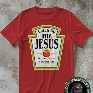 Puede incluir: Camiseta roja con un gráfico de botella de ketchup que dice "Catch Up With Jesus" y "Lettuce Praise & Relish Him Cuz He Loves Me From My Head To-Ma-Toes".