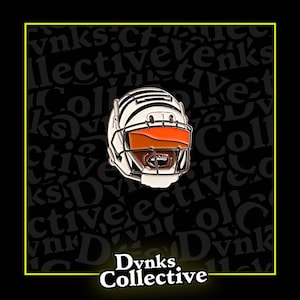 May include: White football helmet with an orange visor and a black face mask. The helmet is on a black background with the text "Dvnks Collective" in white.