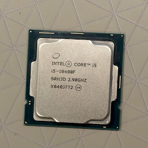 May include: A square Intel Core i5-10400F computer processor with a silver metal heat spreader and a dark green circuit board base. The top surface features etched text reading Intel Core i5, i5-10400F, SRH3D 2.90GHz, and X040J772.