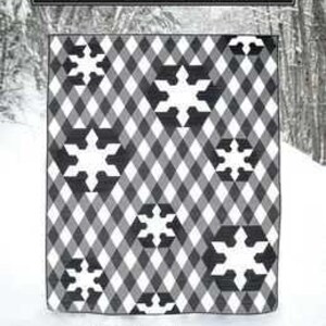 May include: A black and white quilt with a snowflake pattern. The quilt has a checkered background with white snowflake designs. The text "Snowflake Lane" is at the top. The quilt is 63" x 78.5" (twin size).