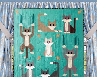 May include: A teal quilt pattern featuring stylized cats in various poses. The quilt, labeled "Cat Scratch," has dimensions of 40" x 40" and 55.5" x 62". The Art East Quilting Co. logo and social media handles are visible.