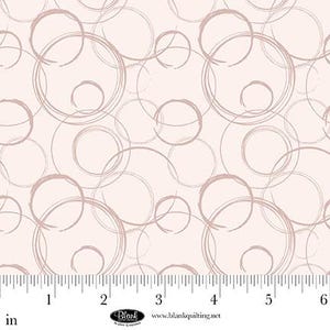 May include: A fabric with a repeating pattern of overlapping, hand-drawn circles in shades of taupe and light brown on a pale pink background. The circles vary in size and are arranged in a seemingly random manner. The fabric has a ruler along the bottom edge.