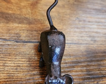 May include: A black cast iron mouse figurine with a long, curved tail. The mouse is standing on a wooden surface.
