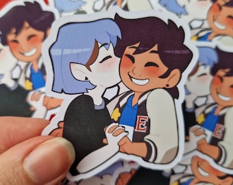 May include: A sticker featuring a cartoon couple, a blue-haired person with a pointed ear and a brown-haired person with a white jacket and a blue shirt with a star and the letter 'E' on it. The couple is hugging and smiling.