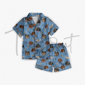 May include: A blue pajama set with a short-sleeved shirt and shorts. The fabric features a repeating pattern of dog faces in various breeds.