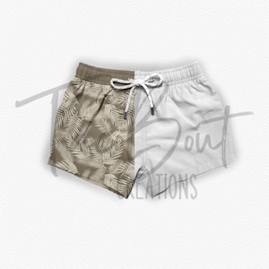 May include: A pair of beige and white swim trunks with a tropical leaf print on one side. The trunks have a drawstring waist.