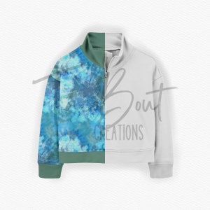 May include: A half-zip sweatshirt with a tie-dye pattern on one side and a solid light gray color on the other side. The tie-dye pattern features shades of blue and green.