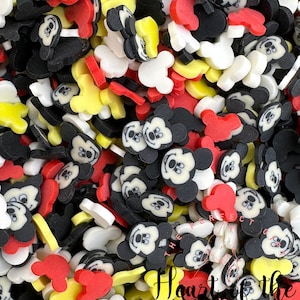 Op de afbeelding: Een grote verzameling kleurrijke Mickey Mouse-thema besprenkeling. De besprenkeling zijn in de vorm van Mickey Mouse's hoofd, oren en een eenvoudige cirkel. De kleuren zijn rood, geel, zwart en wit.