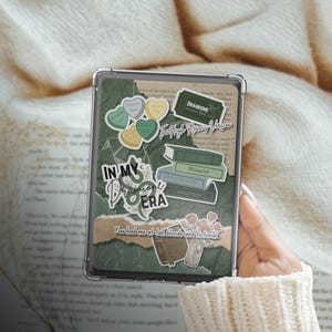 May include: A green and white phone case with a variety of stickers, including a green snake, a ticket that says "Dramoine The High Rewatch Version", and a heart with the text "You had me at tall, blonde and fictional".