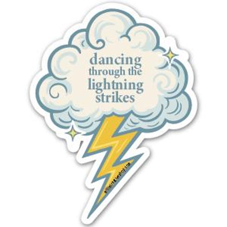 May include: A die-cut sticker featuring a cloud with the text "dancing through the lightning strikes" in a whimsical font. A yellow and blue lightning bolt extends from the cloud, with two small yellow stars. The sticker has a white border.