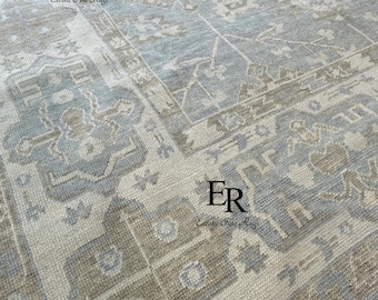 Könnte beinhalten: Nahaufnahme eines hellblauen und beigefarbenen Teppichs mit Muster. Der Teppich zeigt ein detailliertes Design mit geometrischen und floralen Motiven. Der Teppich hat ein weiches, strukturiertes Aussehen, mit dem Text "ER Exotic Fine Rugs" in den Ecken.