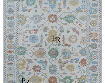 May include: A white rug with a colorful geometric pattern. The rug has a border with a repeating design. The rug has the text "Exotic Fine Rugs" and "ER" in the corners.