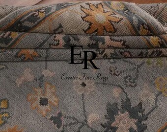 May include: Folded rug with a floral pattern in grey, yellow, and peach. The rug has a detailed design and the text "Exotic Fine Rugs".