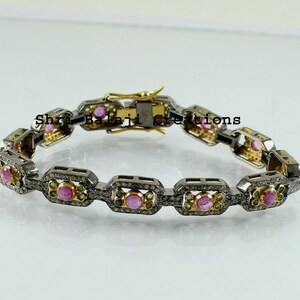May include: A silver and gold bracelet with a chain link design. The bracelet is set with pink and green gemstones and small diamonds. The bracelet has a clasp closure.