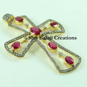 May include: A gold cross pendant featuring a diamond and ruby design. The cross is set with small diamonds and has five ruby stones. The pendant is signed "Shri Balaji Creations".