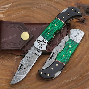 May include: Two pocket knives with green and black handles. One knife has the name "Arther" engraved on the handle. The other knife has the name "Jay" engraved on the handle.