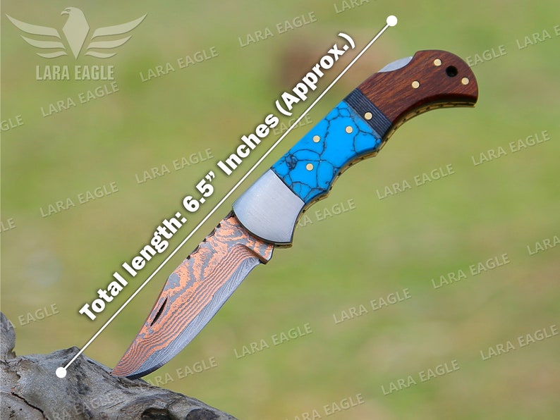 Op de afbeelding: Een vouwmes met een turquoise en koperkleurig gepatenteerd blad en een bruin houten handvat. Het mes is 16,5 cm lang.