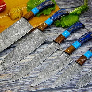 May include: Set of six kitchen knives with blue and brown handles. The blades are made of Damascus steel and have a wavy pattern.