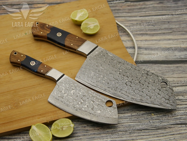 May include: Two kitchen knives with wooden handles and a patterned steel blade. The knives are on a wooden cutting board with lemons.