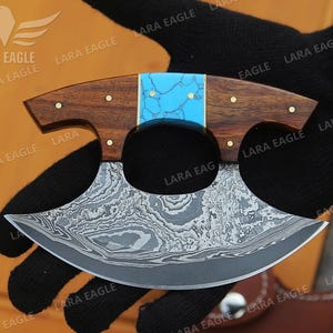 May include: A blue and brown handled knife with a patterned steel blade. The blade is curved and has a unique shape.