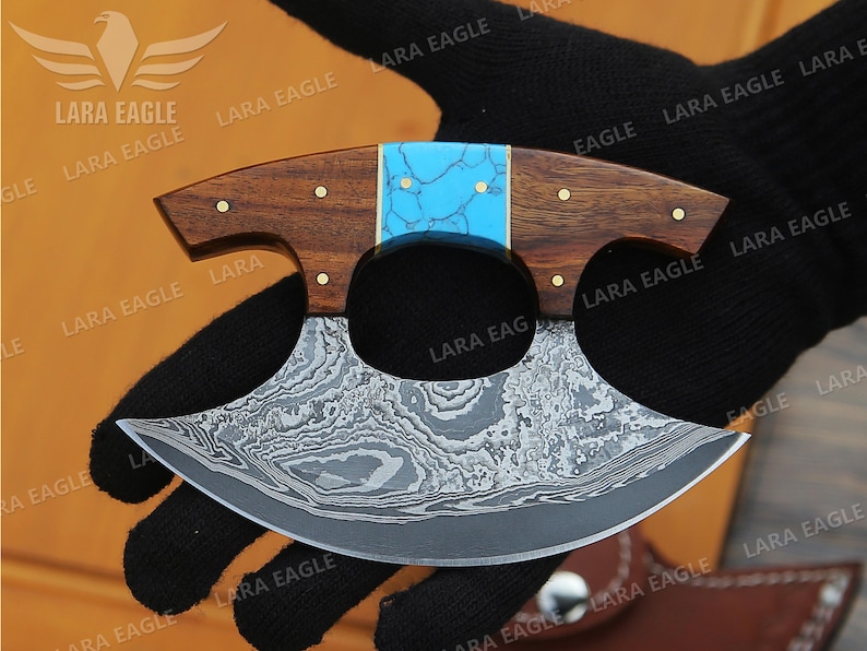 May include: A blue and brown handled knife with a patterned steel blade. The blade is curved and has a unique shape.