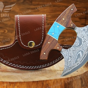 May include: A handmade Damascus steel cleaver with a turquoise and wood handle. The cleaver is in a brown leather sheath.