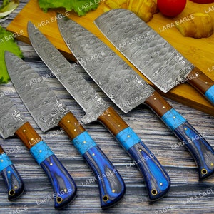 May include: Set of five kitchen knives with blue and turquoise handles. The knives have a Damascus steel blade pattern and are arranged on a wooden surface.