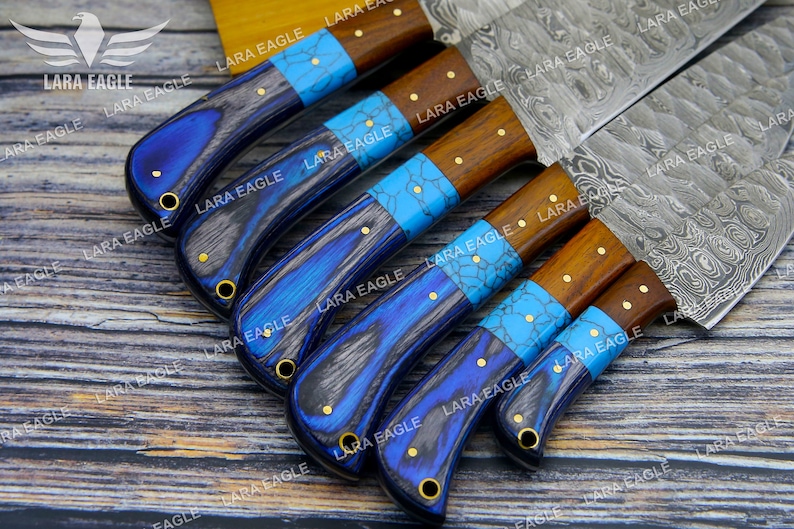 May include: A set of six kitchen knives with blue and brown handles. The blades are made of Damascus steel and have a wavy pattern. The handles are made of wood and have a blue and turquoise inlay.