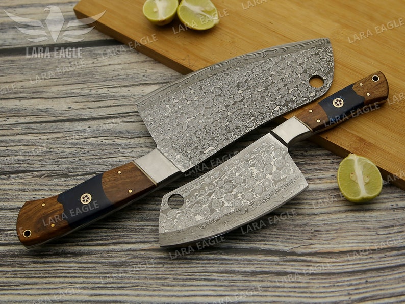 May include: Two stainless steel cleavers with wooden handles. The cleavers have a hammered finish and a decorative pattern. The handles are brown with black accents.