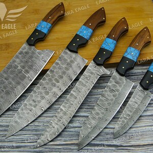 May include: Five kitchen knives with wooden handles and blue and black accents. The blades are made of patterned steel.