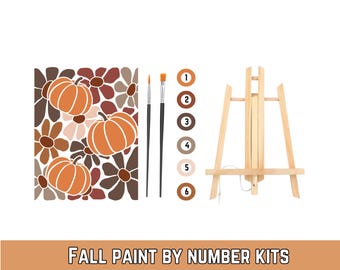 May include: A paint-by-number kit with a fall theme. The kit includes a canvas with a pumpkin and floral design, paintbrushes, numbered paint pots, and a wooden easel. The text "FALL PAINT BY NUMBER KITS" is at the bottom.