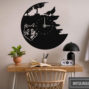 May include: Black metal wall clock with a wolf design. The clock features a wolf howling at the moon and a wolf's head. The clock is mounted on a white wall.