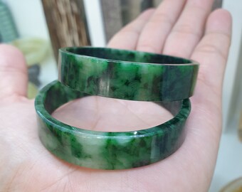 May include: Two jade green bangles with a marbled pattern. The bangles are stacked on top of each other.