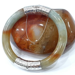 Può includere: Un braccialetto di giada con una fascia in argento martellato. Il braccialetto è verde, marrone e bianco.