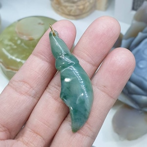 May include: A green jade pendant carved in the shape of a leaf with a gold bail.