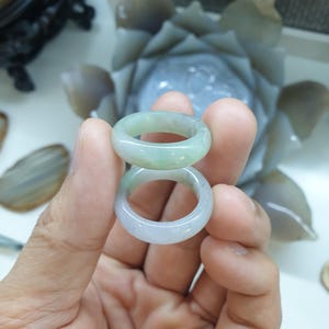 Könnte beinhalten: Zwei Jade-Ringe, einer auf dem anderen gestapelt. Die Ringe sind hellgrün und haben eine glatte, polierte Oberfläche.