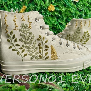 May include: White high-top canvas sneakers with green and yellow embroidered floral designs.