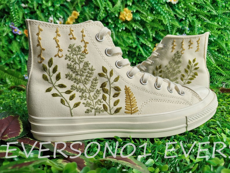 May include: White high-top canvas sneakers with green and yellow embroidered floral designs.
