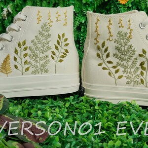 May include: White high-top canvas sneakers with green and yellow embroidered floral designs.