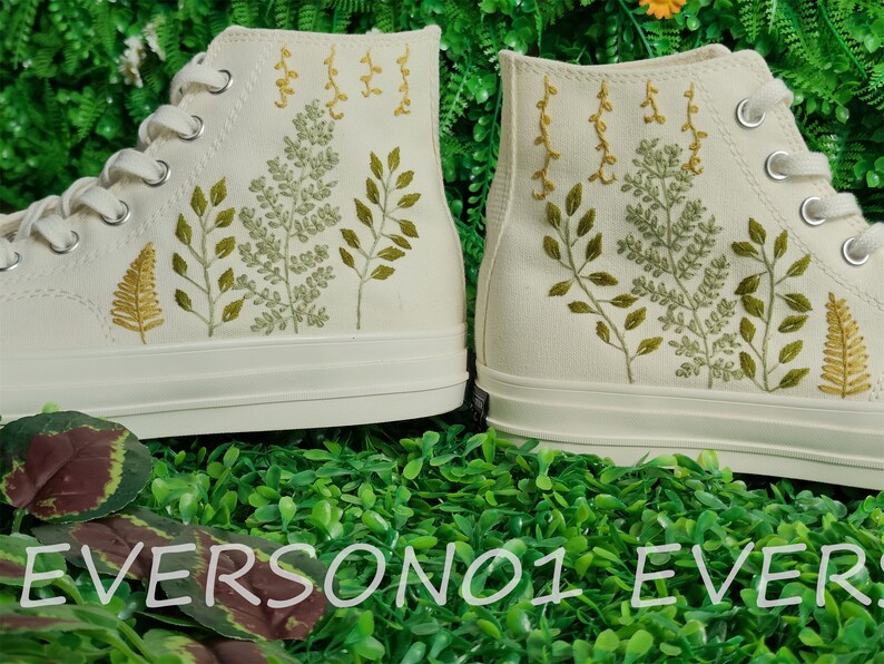 May include: White high-top canvas sneakers with green and yellow embroidered floral designs.